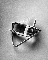 De Patta brooch with a Sperisen double lens "opti-cut" smoky quartz. When observed by a spectator, the stone creates a "see through" effect that distorts and gives the illusion of movement to the chased decorated surface behind the gemstone.Photo by Margaret De Patta